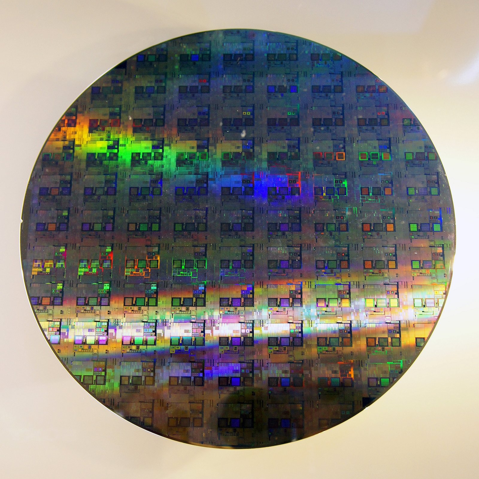 A patterned silicon wafer showing many repeated die under colorful diffracted light